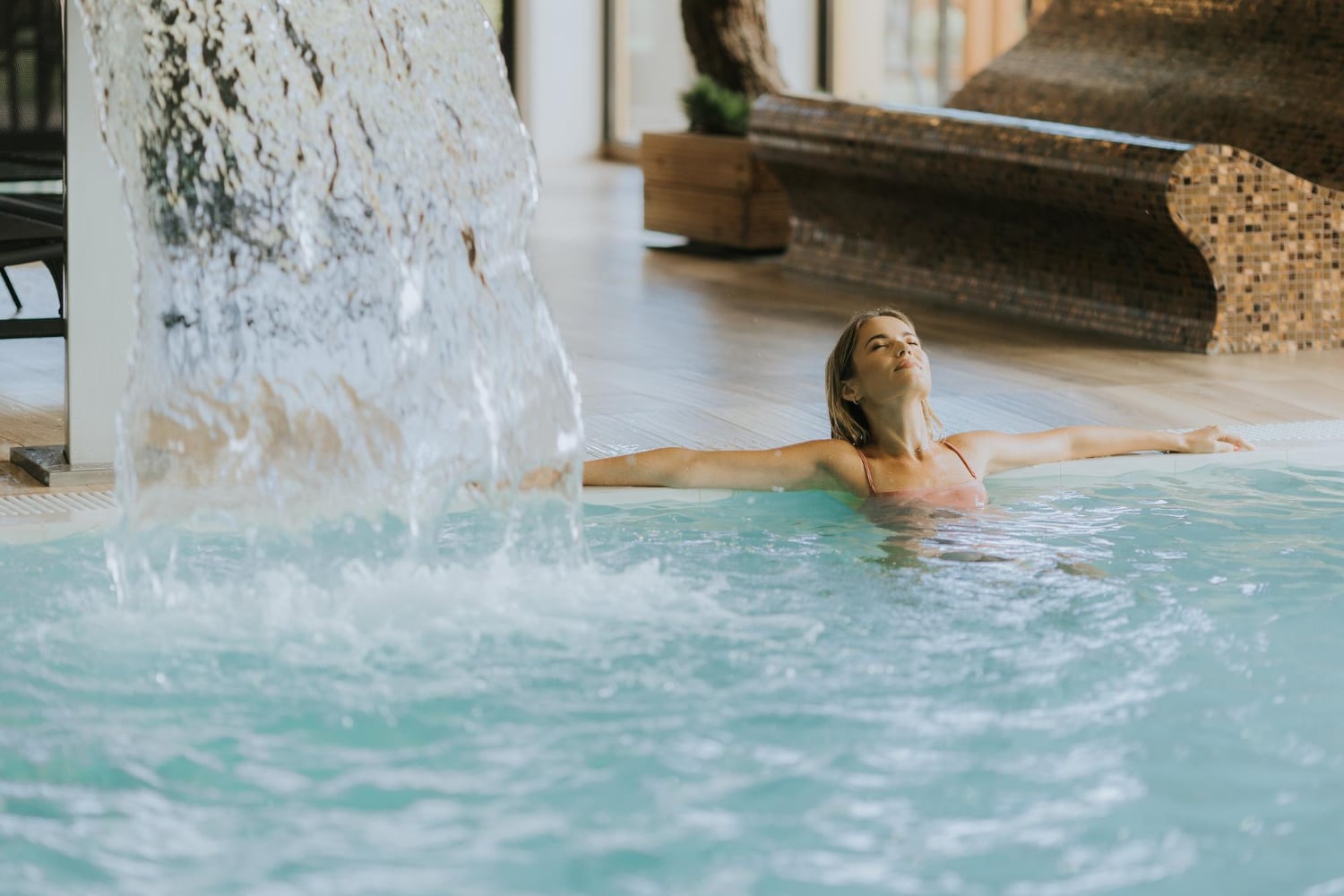 Jolie jeune femme se relaxant dans la piscine intérieure